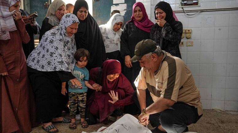 فلسطينيون يتجمعون حول جثث أثناء التعرف على الضحايا في مستشفى «شهداء الأقصى» في دير البلح بعد القصف الإسرائيلي